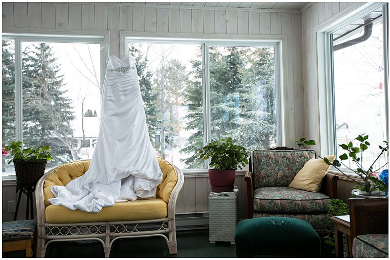 The wedding dress hanging in a screened porch