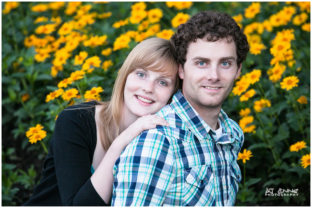 The engaged couple in front of a daisy garden