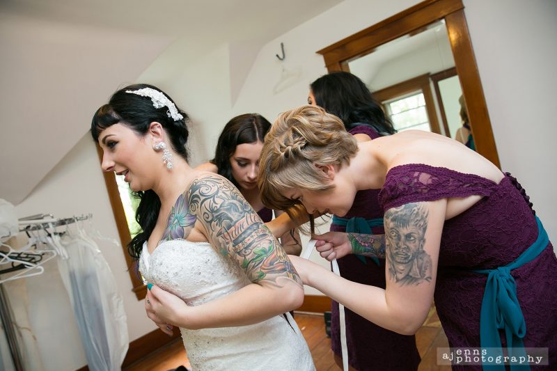 the girls all helping put on the brides dress