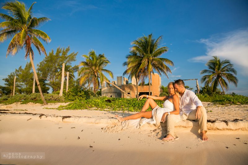 The couple sitting on the shore with Mexican ruins in the background