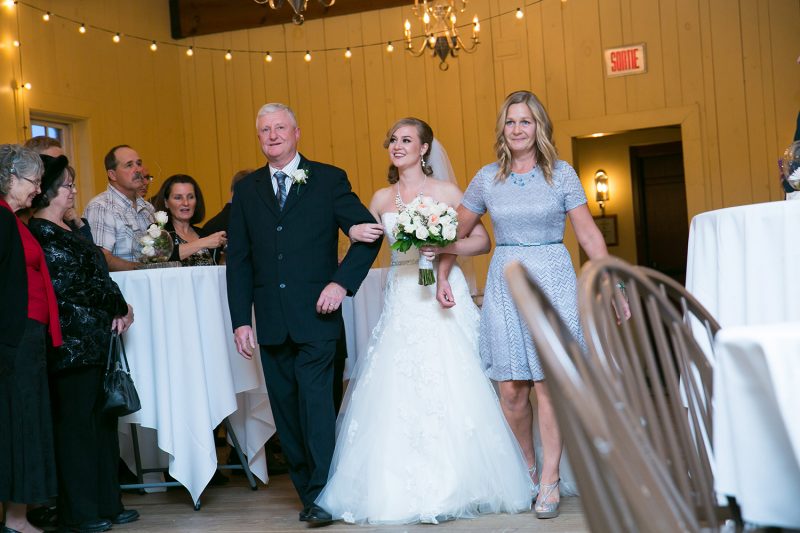 The bride walking down the isle with both her parents