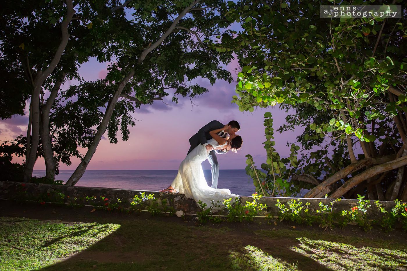 The couple with a romantic dip on the brick wall and the sunset in the background