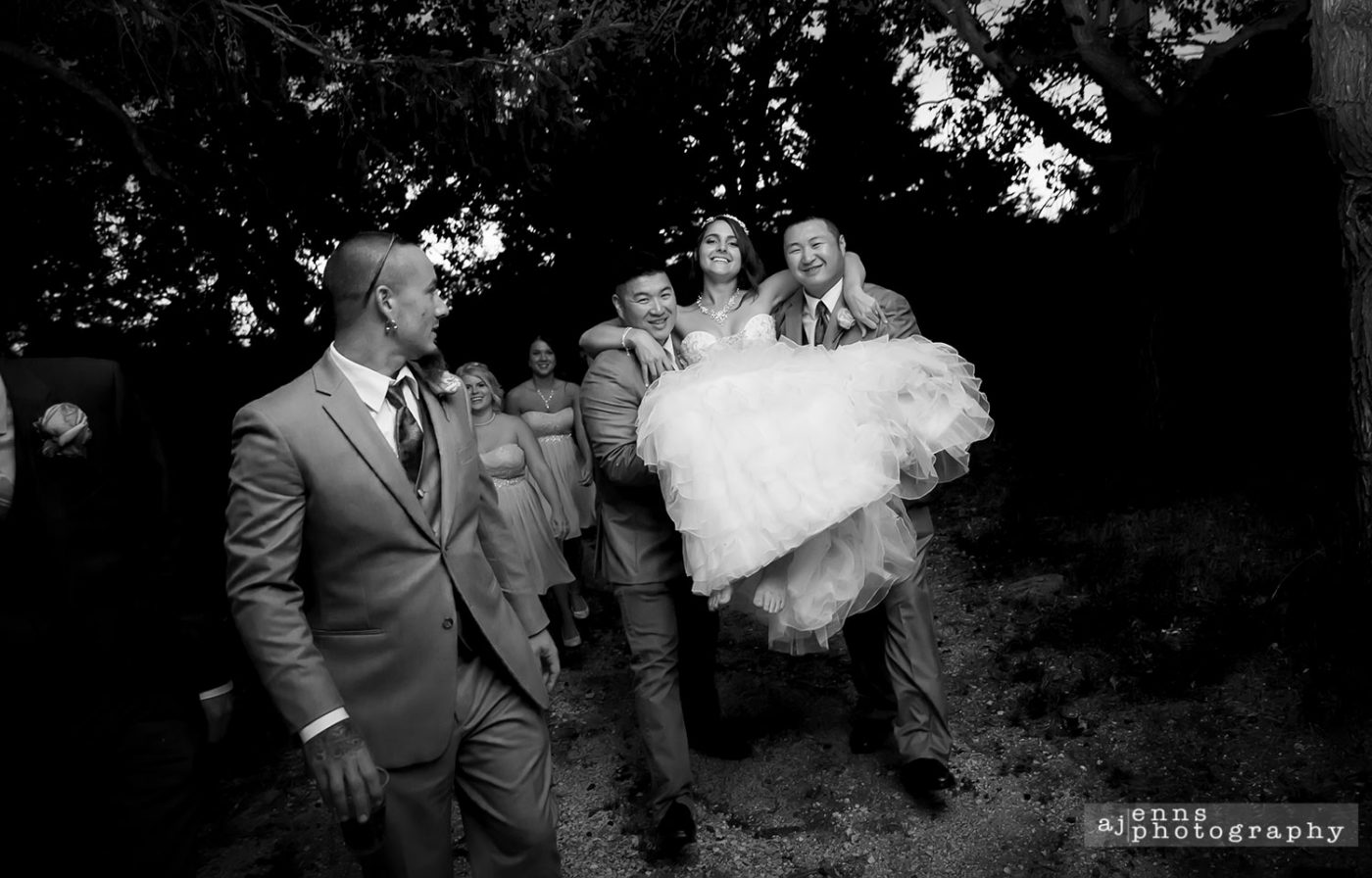 Felicia being carried by her groomsmen over some mud in her wedding dress