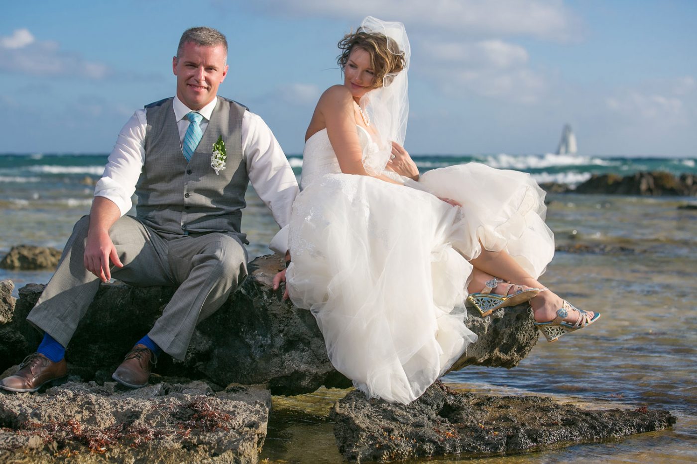 The bride looking at groom while on the rocks on the beach