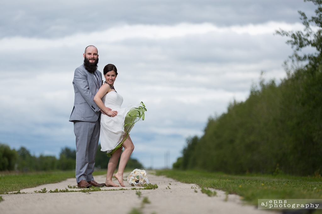 The newlyweds standing on path in the back woods while the bride fills her dress up