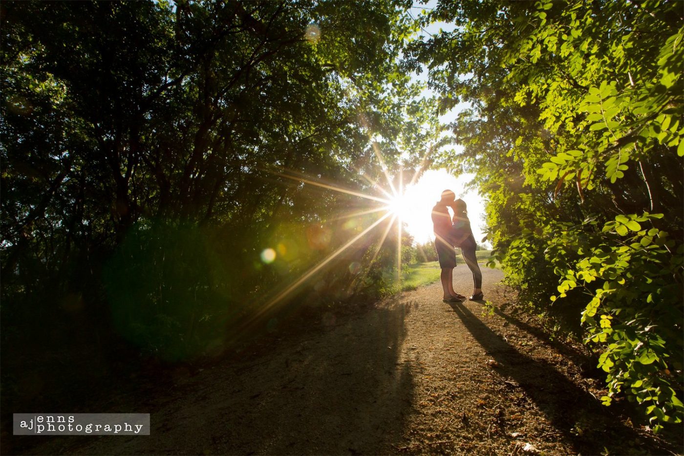 A special kiss during sunset under a canopy of trees