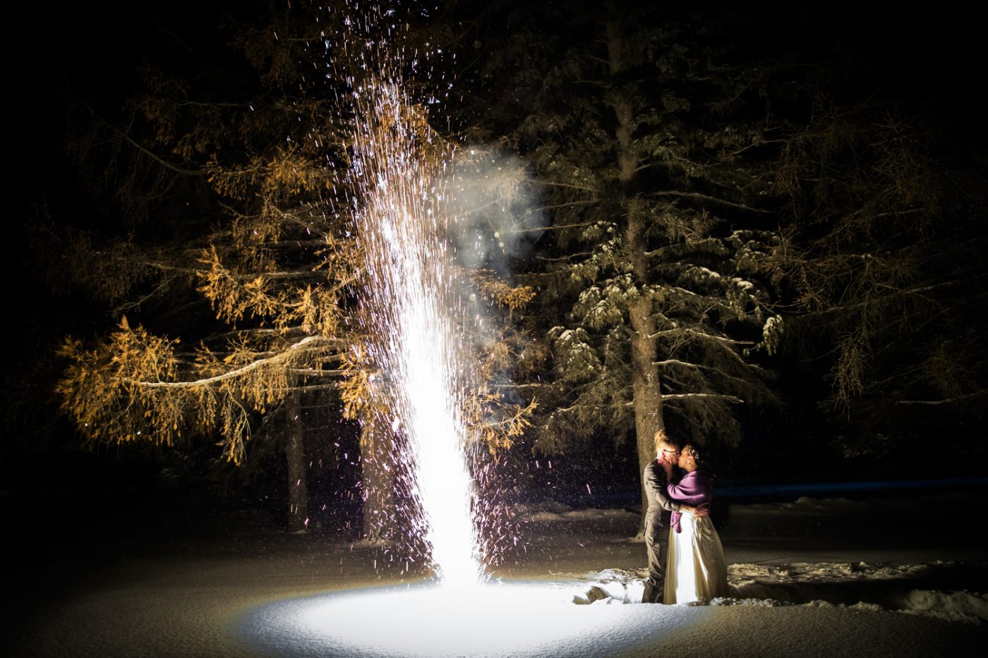 The couple kisses while a few feet away is a 30 foot hight sparkler firework show