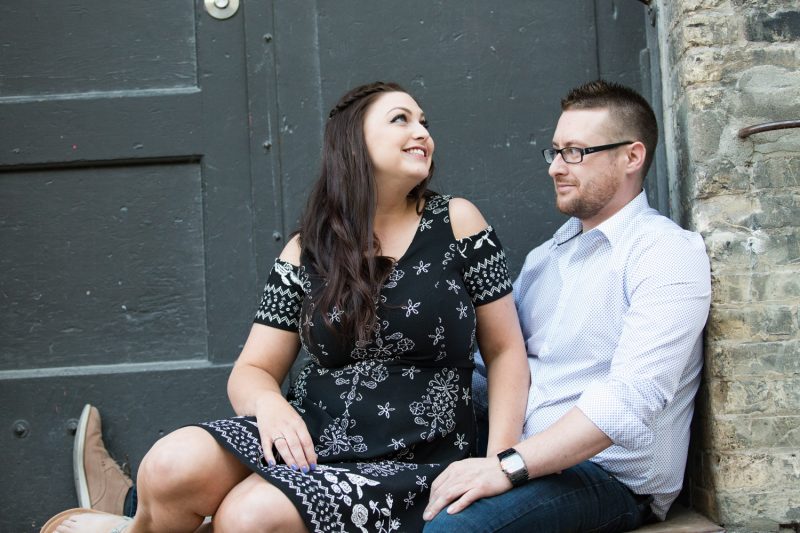 The couple joking around while sitting against an old loading dock in the Exchange District