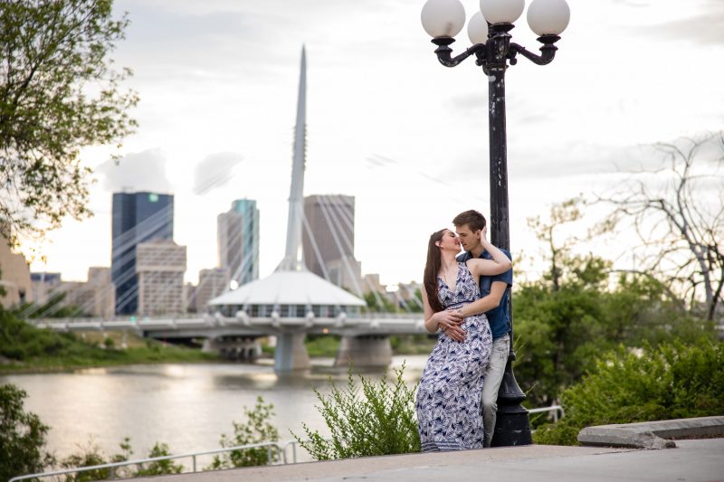 The couple kissing as they lean against a light post with the esplanade riel bridge in the background
