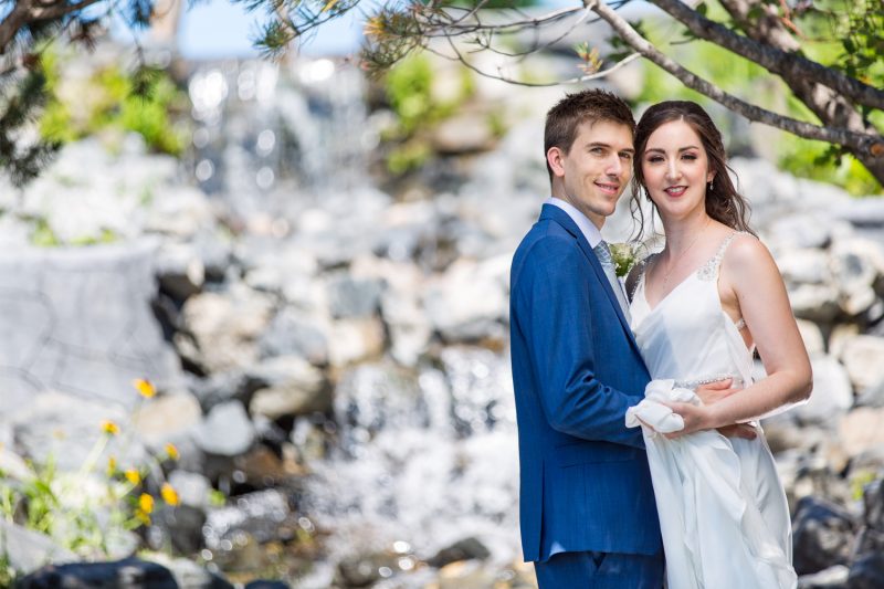 The couple hold each other with a waterfall in the background