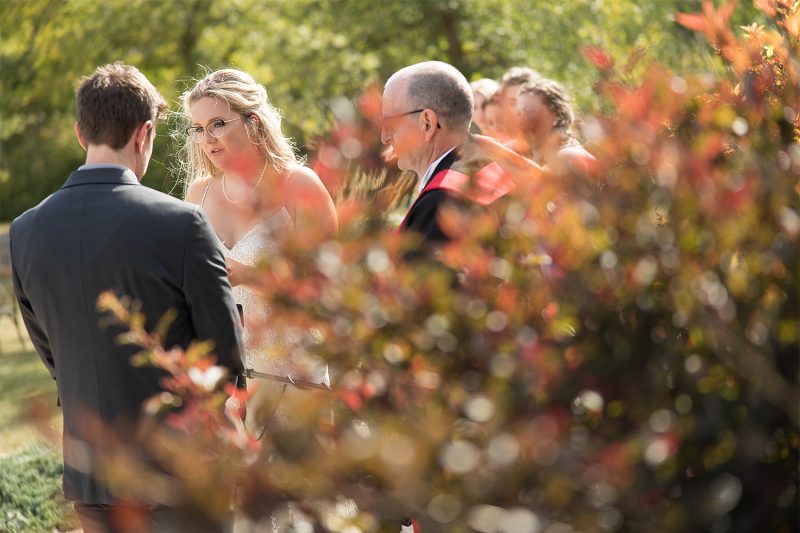 Looking through some orange leaves at the bride reading her vows