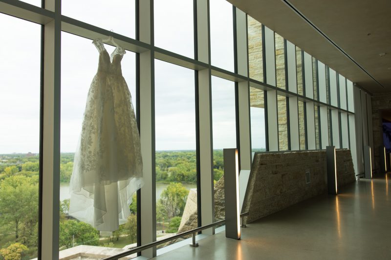 Julia's wedding dress hanging in front of a large set of windows