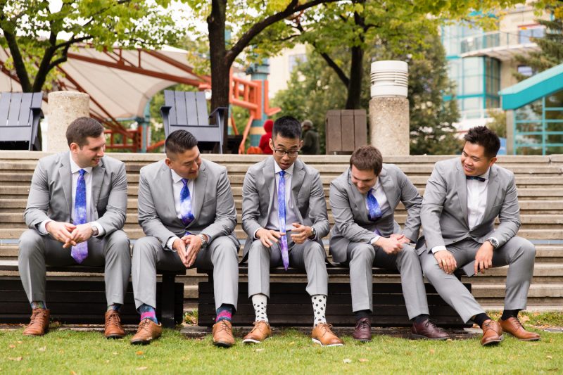 Chris enjoying a story with his groomsmen on a park bench at the forks