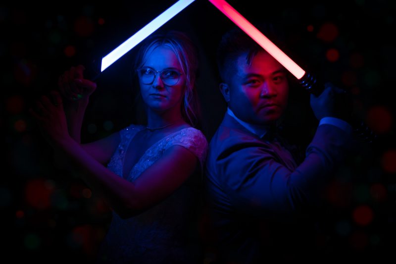 The couple holding light sabers with their backs to each other