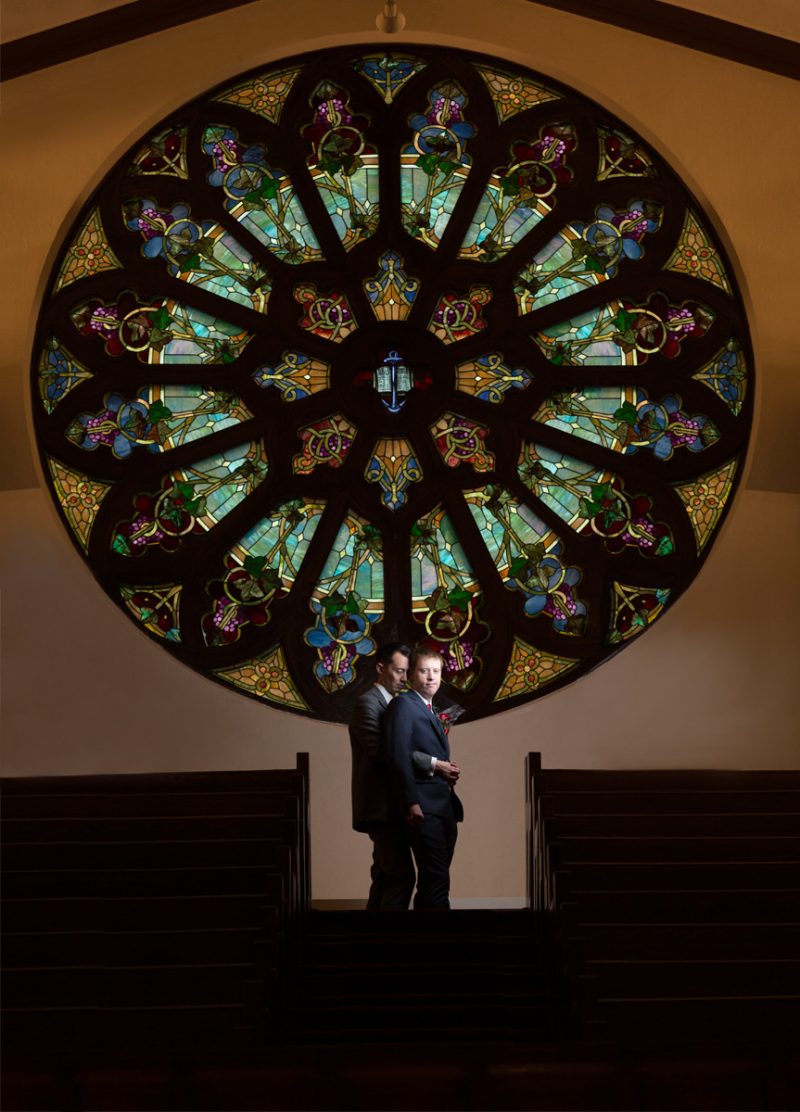 The couple in front of the huge circular stained glass piece in the balcony