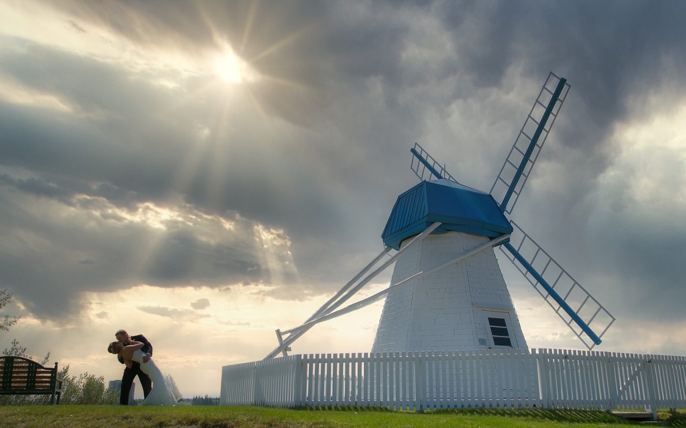 Keith dipping Joelle under a cloudy sky beside a windmill