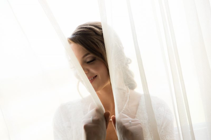 The bride looking through the window curtains