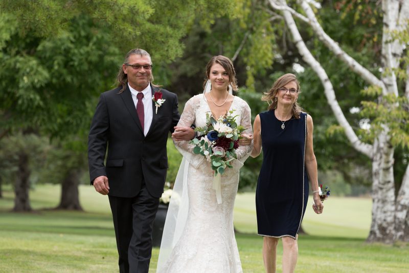 The bride and her parents walking down the isle at Elmhurst golf club