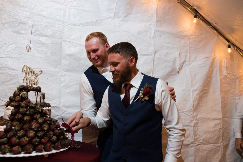the groomsmen holding hands while also cutting the cake