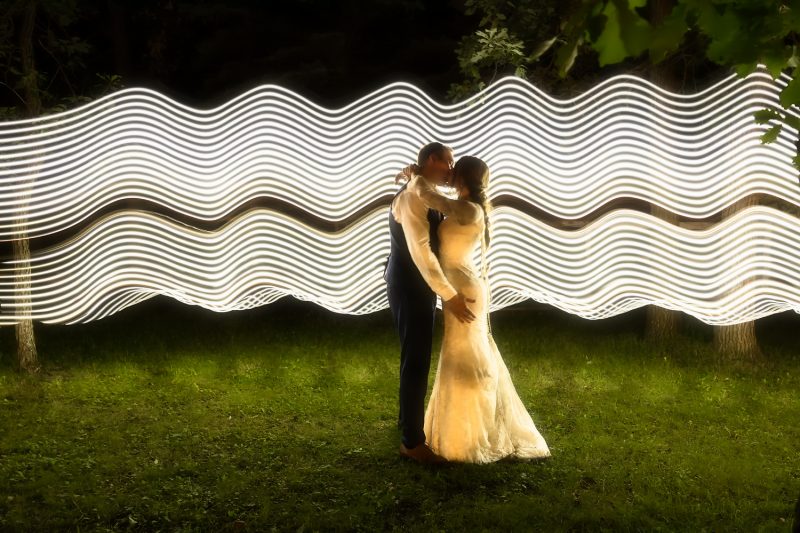 The couple kissing while long wavy lines of light lite them up