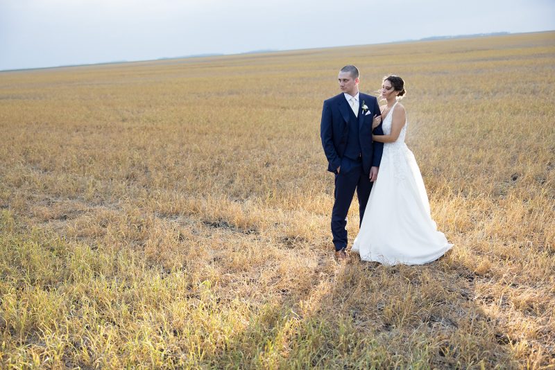 The couple standing in a harvested wheat field
