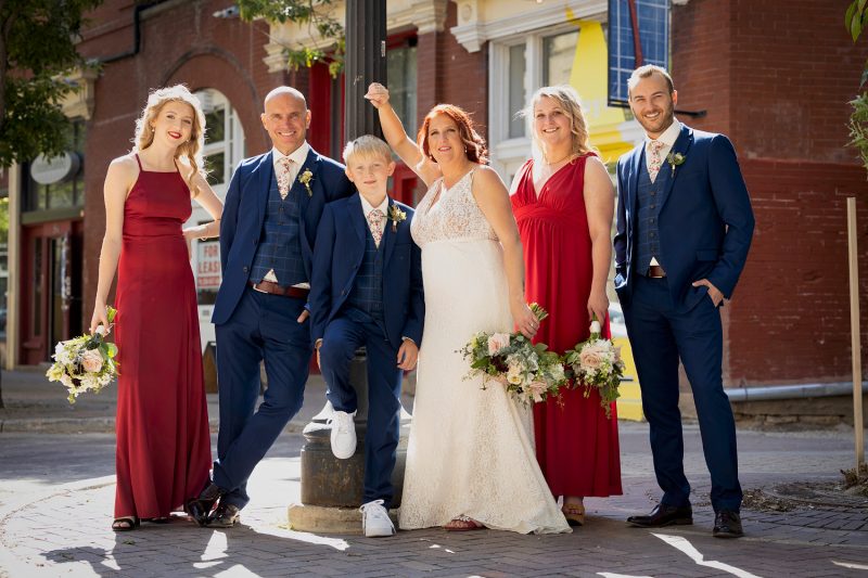 The bridal party poses on the street with a light post