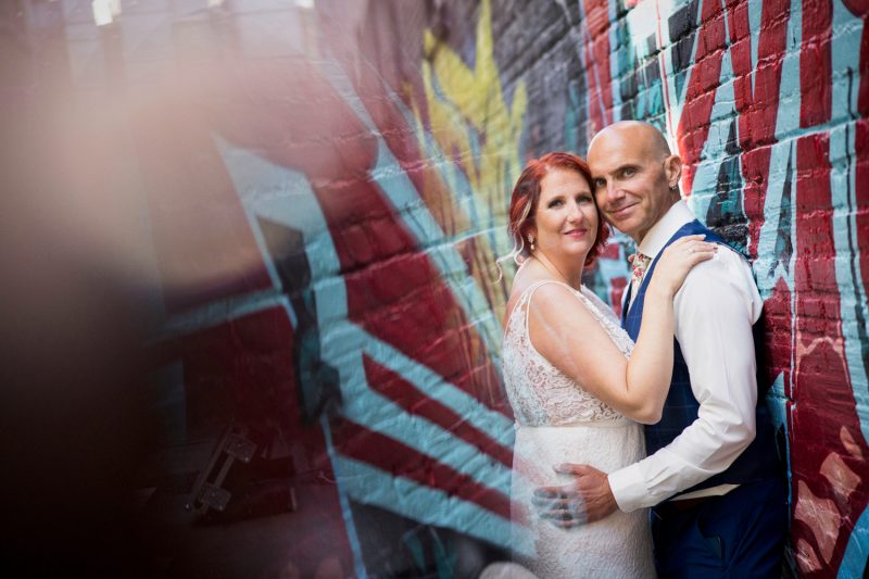 Carrie and Trevor leaning against each other by a graffiti wall and light reflections