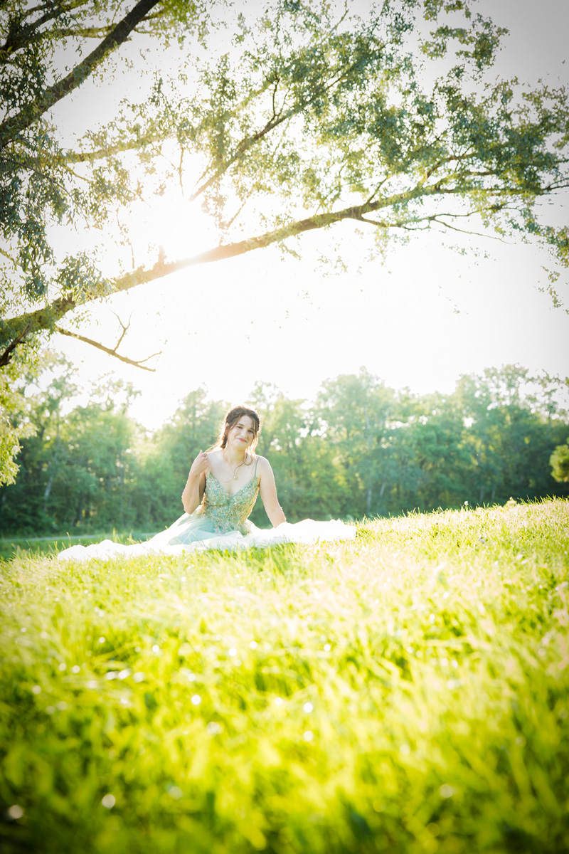 Dawson sitting under a tree in the setting sun with her dress on the grass