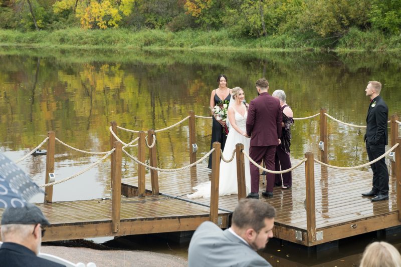 The couple standing on a dock during the ceremony at Rivers Edge Resort