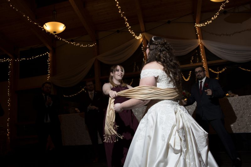 the maid of honour wrapping her scarf around the bride on the dancefloor