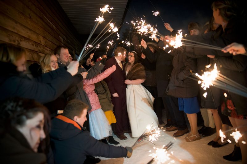 Smiles under an umbrella of sparklers held by guests.