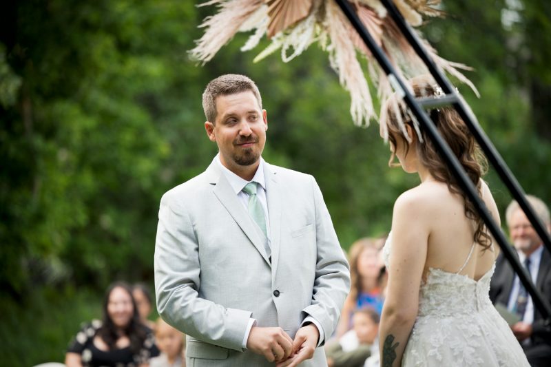 The groom smiles while he hears the vows