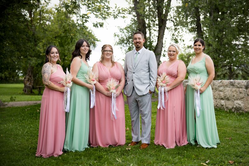 The groom standing with the bridesmaids