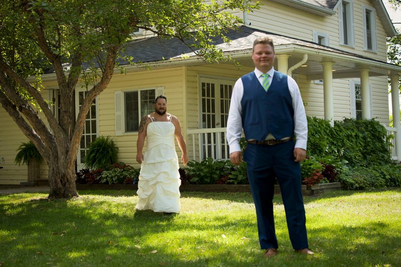 A groomsmen wearing a wedding dress walks up as a prank for the first look