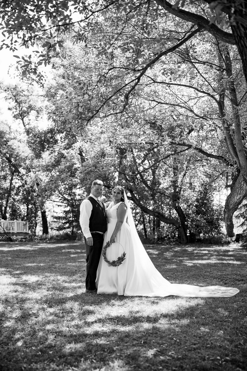 The bride and groom in black and white standing close outside the farm house at Evergreen Village