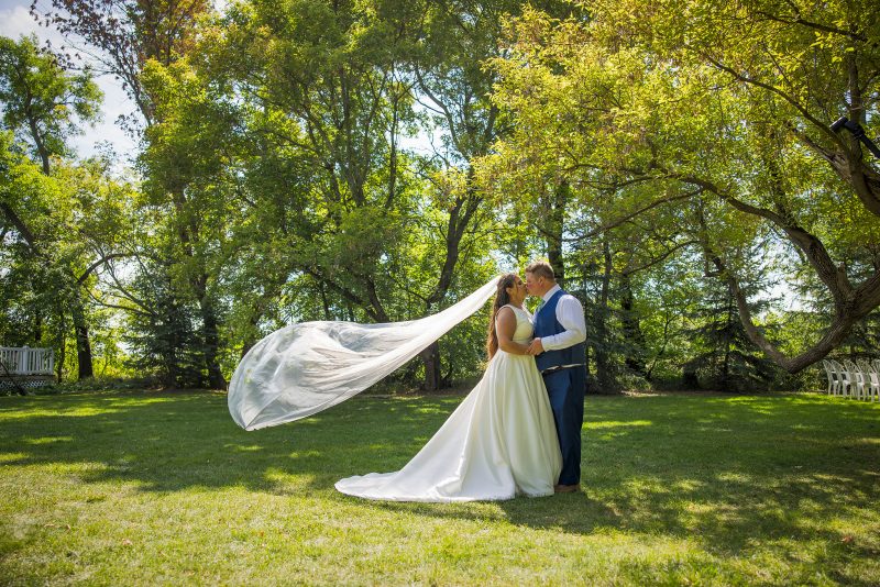 The bride and groom kissing while the veil floats effortlessly in the wind