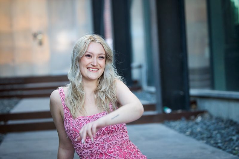 A person sitting on a chair, wearing a pink dress with their face.